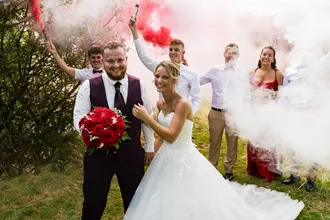 Mariés posant avec invités et fumigènes rouges