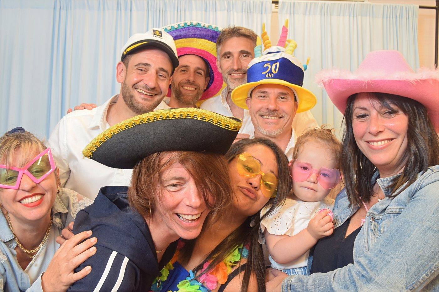 Invités coiffés de chapeaux et d'un sombrero posant au photobooth d'un anniversaire de 50 ans