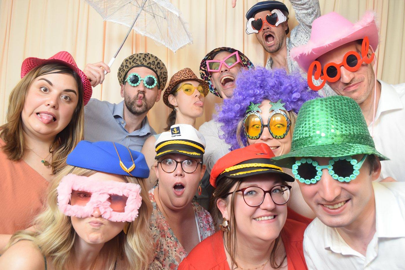 Invités de mariage déguisés avec chapeaux et lunettes faisant des grimaces devant le photobooth