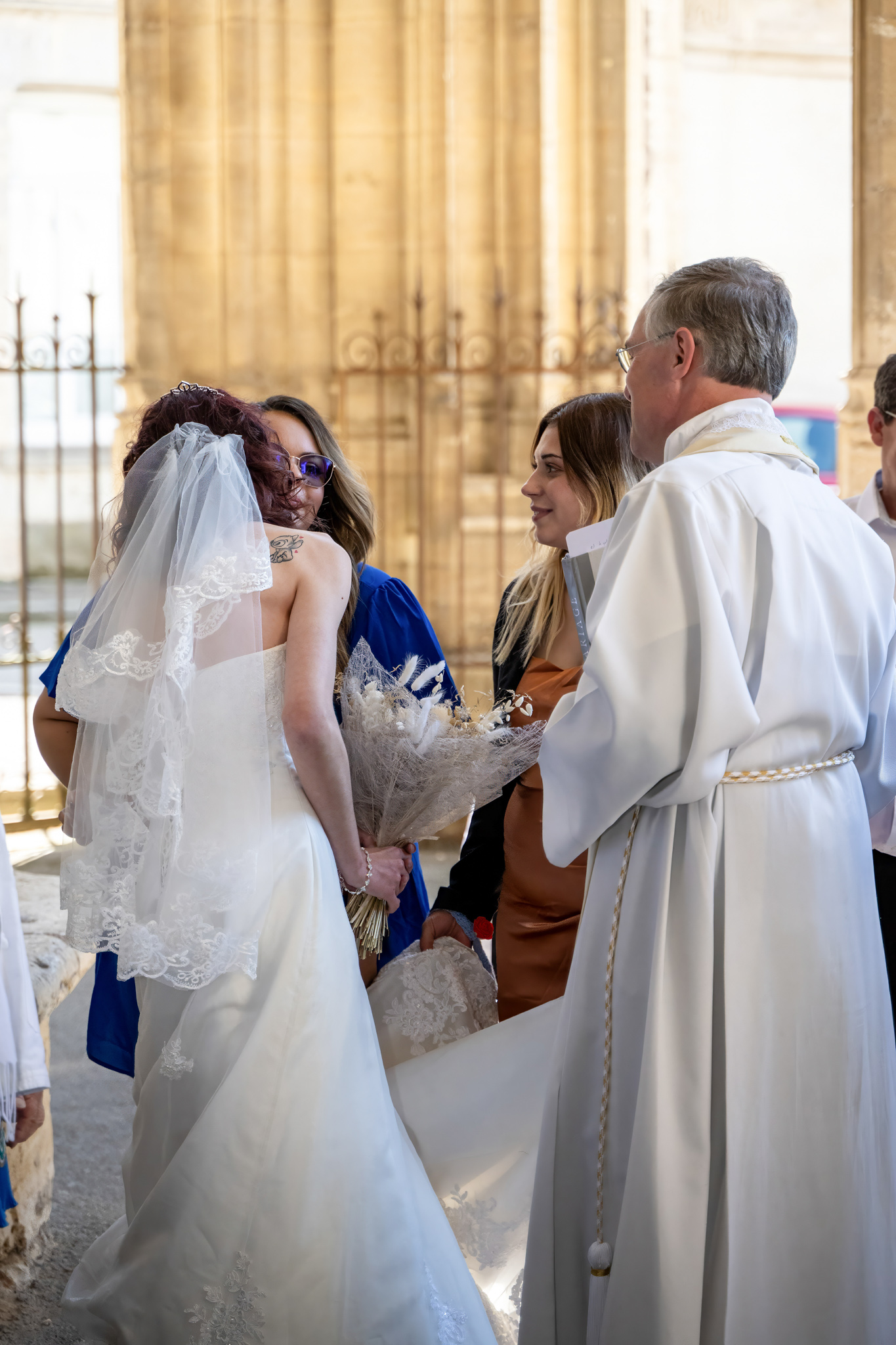 Mariée avec bouquet de fleurs séchées en discussion avec le prêtre