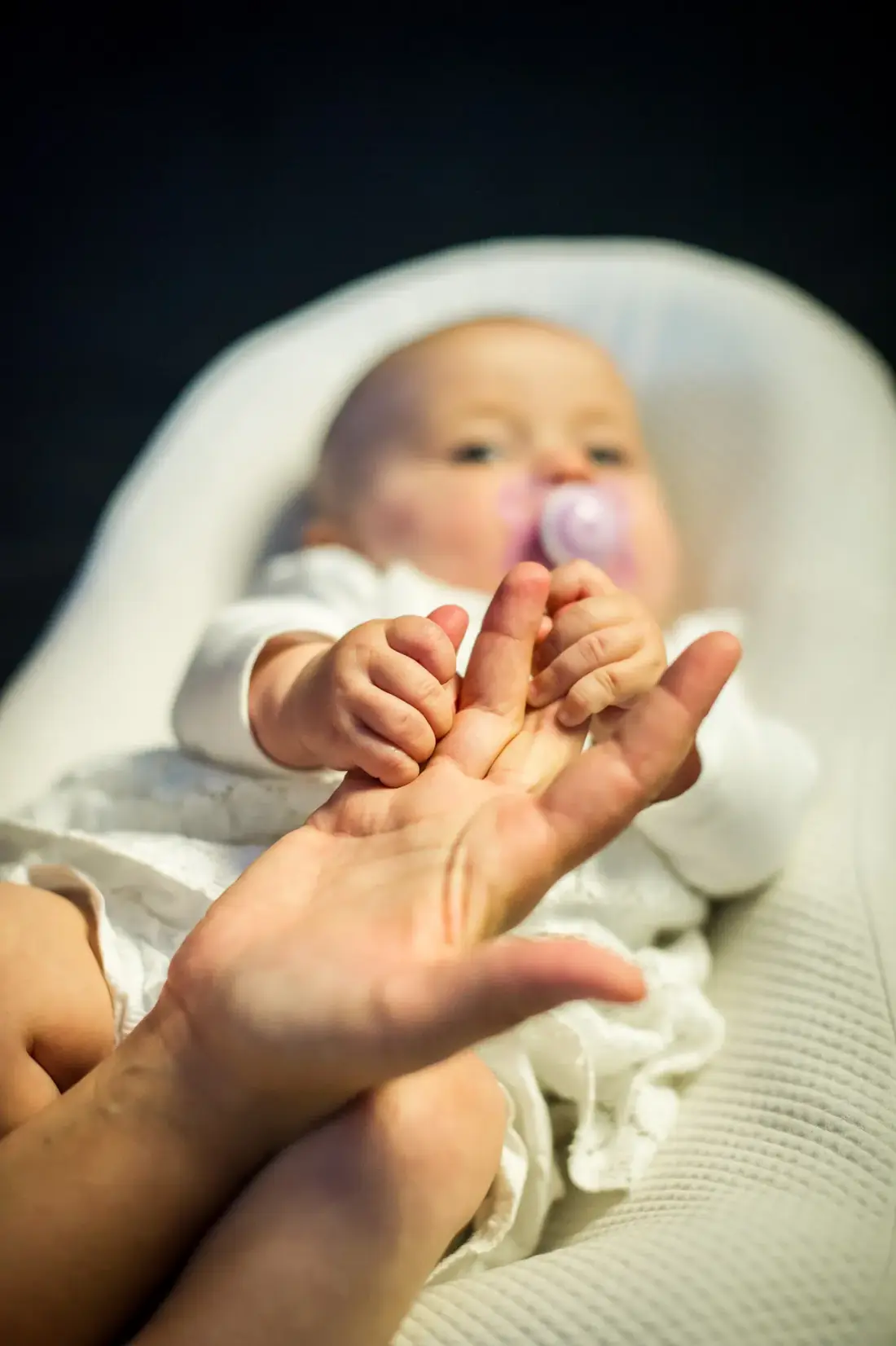 Le bébé tient les doigts de sa maman dans son cocon