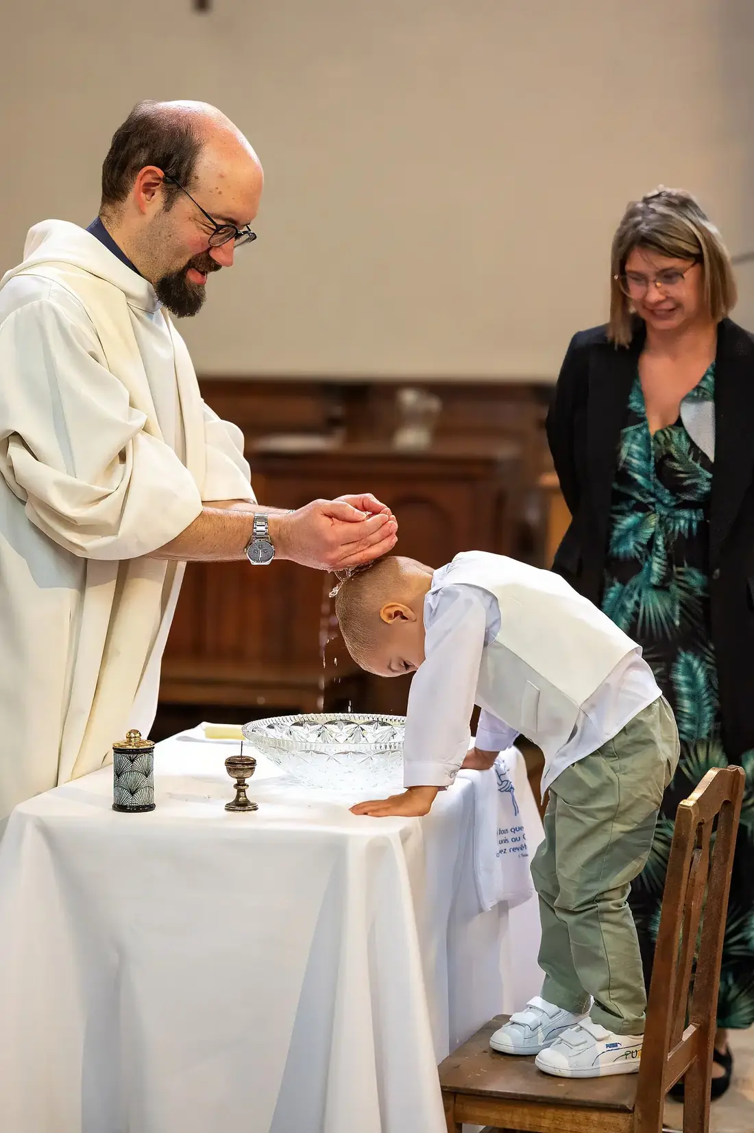 Le prêtre verse l'eau sur la tête de l'enfant