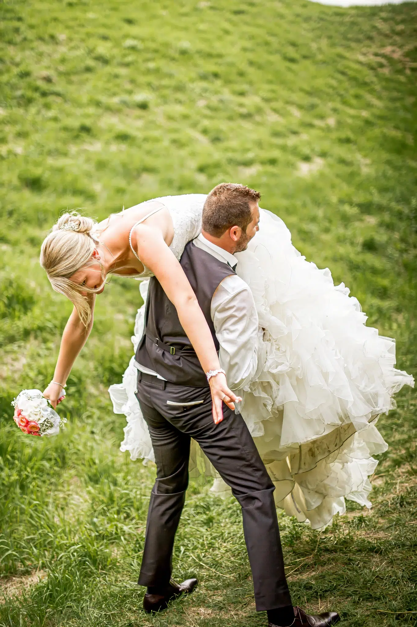 Marié portant la mariée sur son épaule dans l'herbe – Trash the Dress
