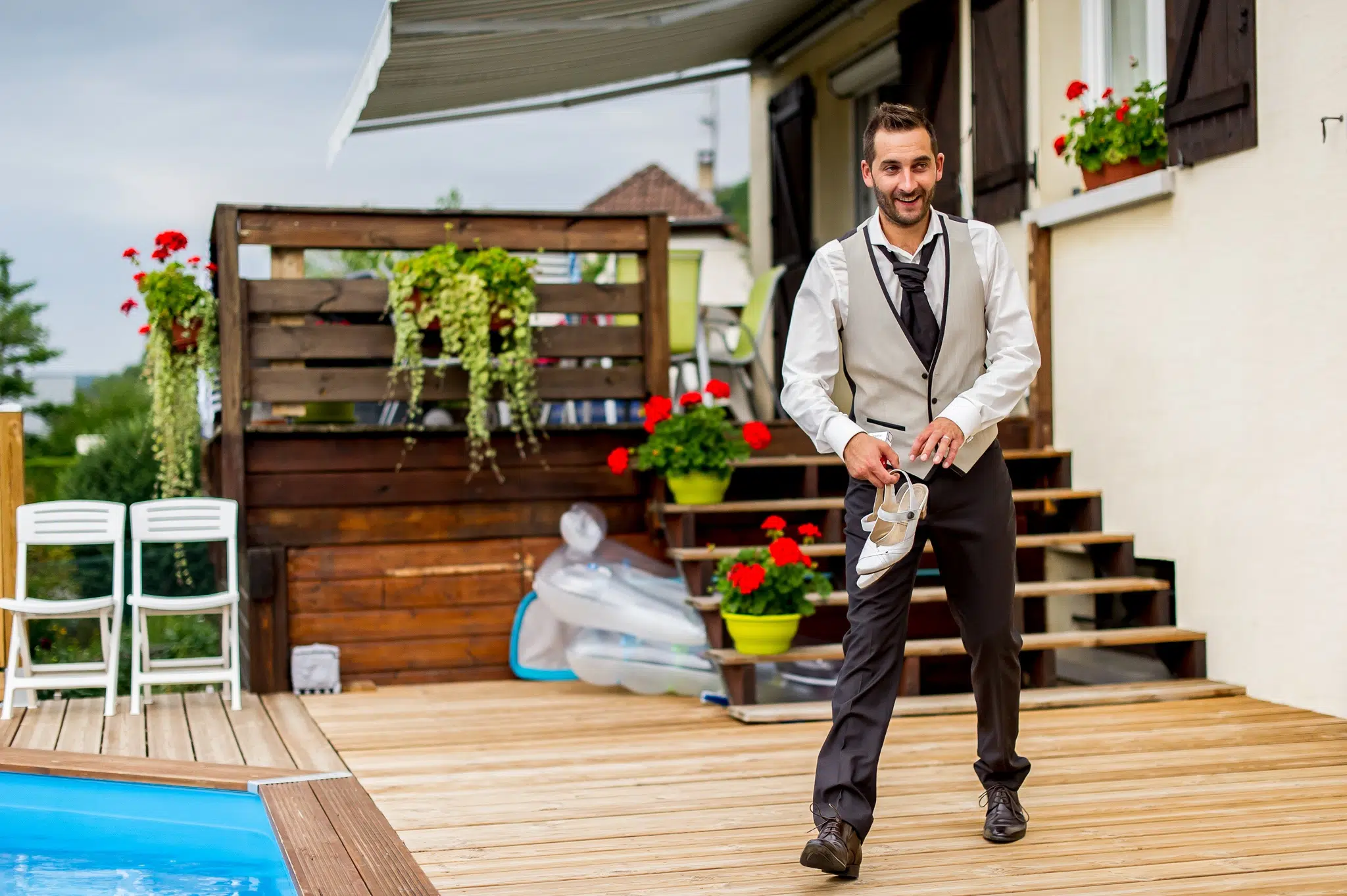 Marié tenant les chaussures de la mariée près de la piscine – Trash the Dress