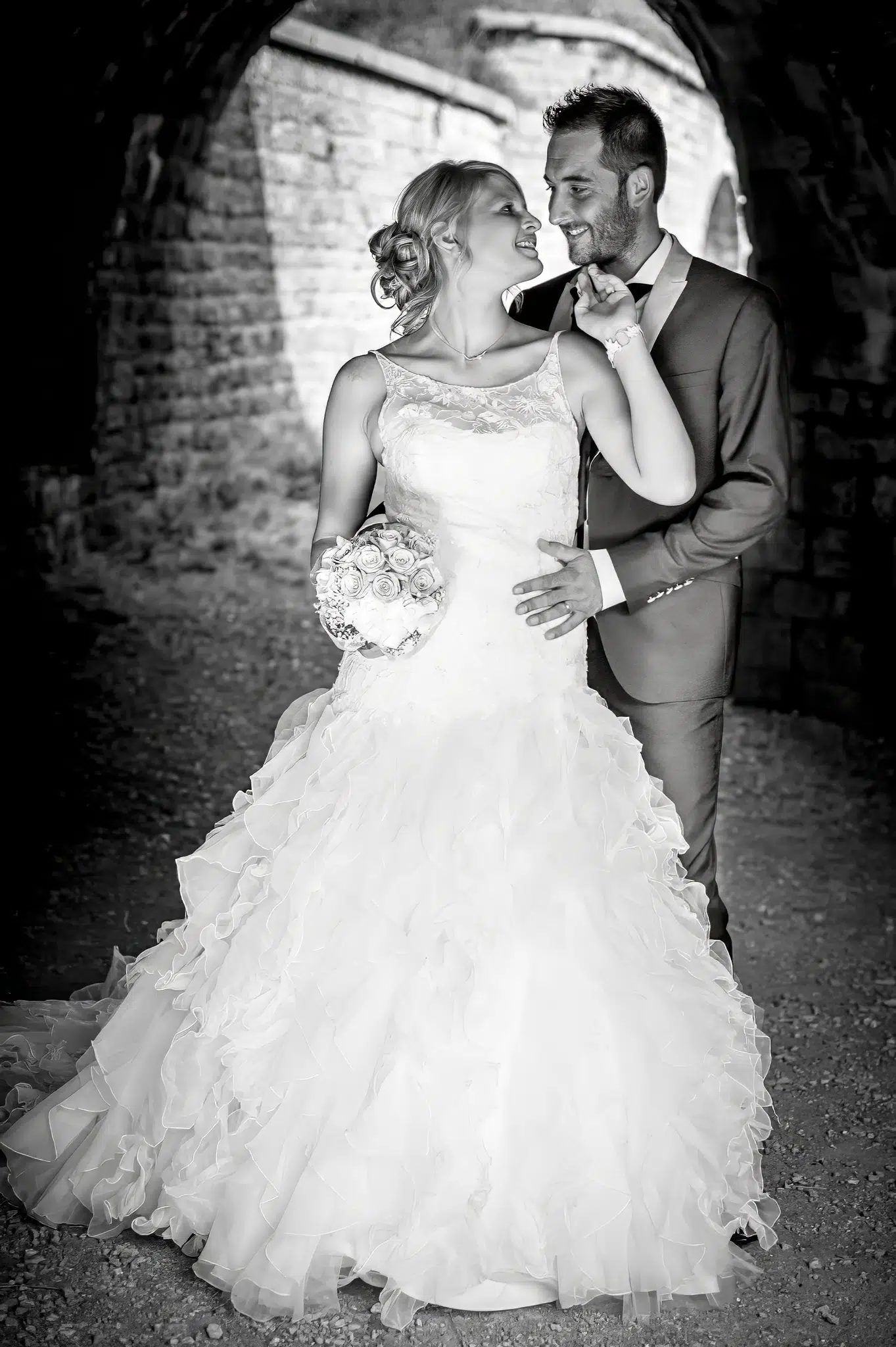 Mariés s'enlaçant sous une arche de pierre – Trash the Dress